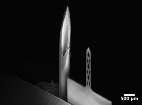 開孔鈦基微針（200um寬，50um厚，1500um長）和26G皮下注射針（外徑464um）對比的掃描電子顯微鏡照片